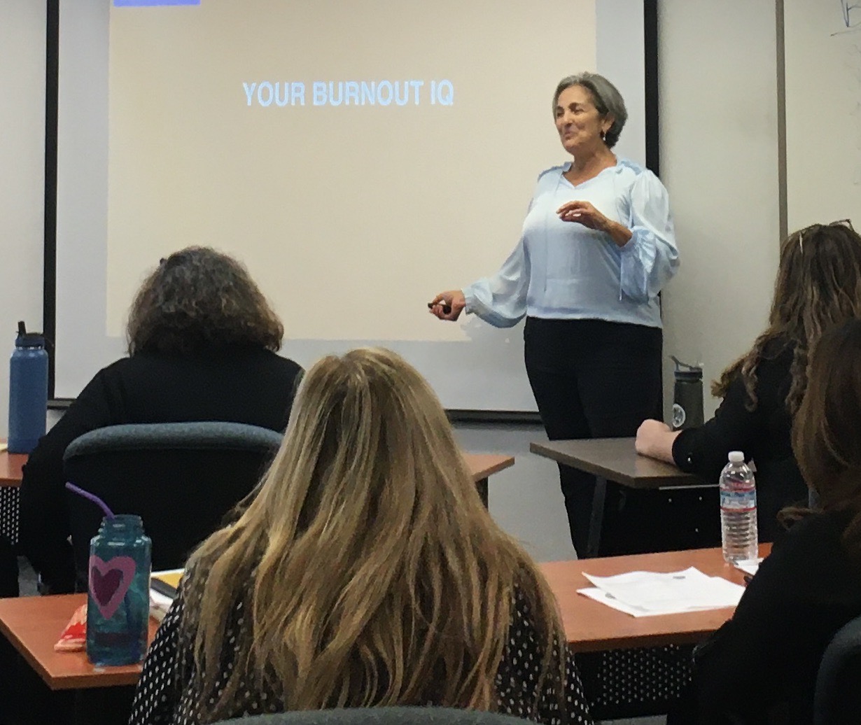 Terre presenting a workshop in person. Board reads "burnout IQ"
