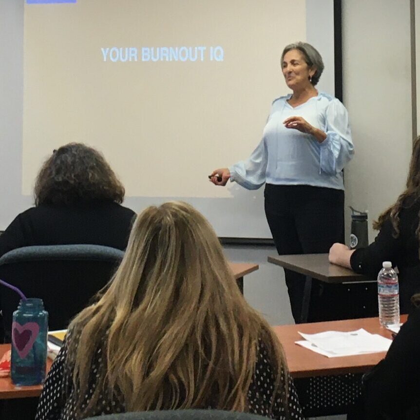 Terre presenting a workshop in person. Board reads "burnout IQ"